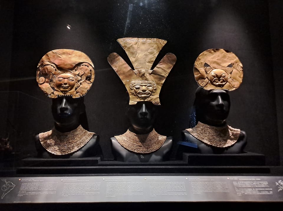 Drei goldene Inka Kronen vor schwarzem Hintergrund in einem Museum.