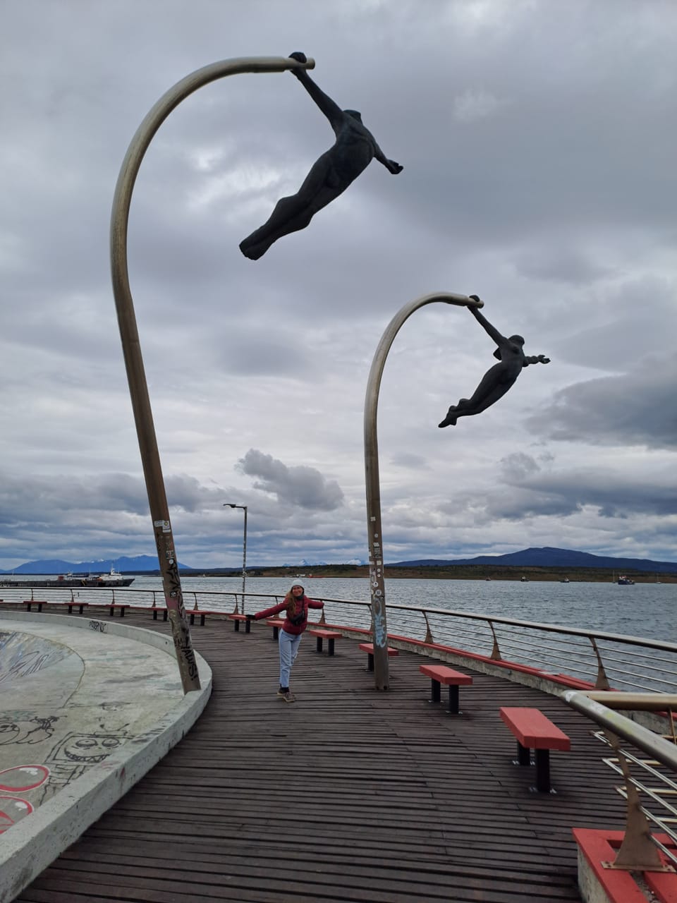 Zwei nackte fliegnde Skulpturen am Wasser.