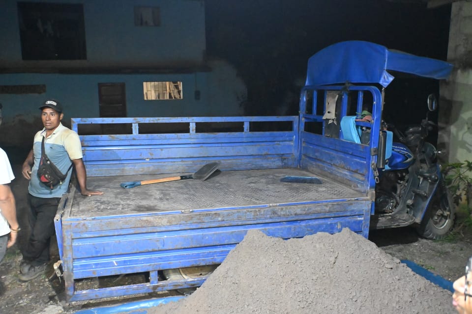 Der abgeladene Motorrad-LKW mit einem Haufen Sand davor.